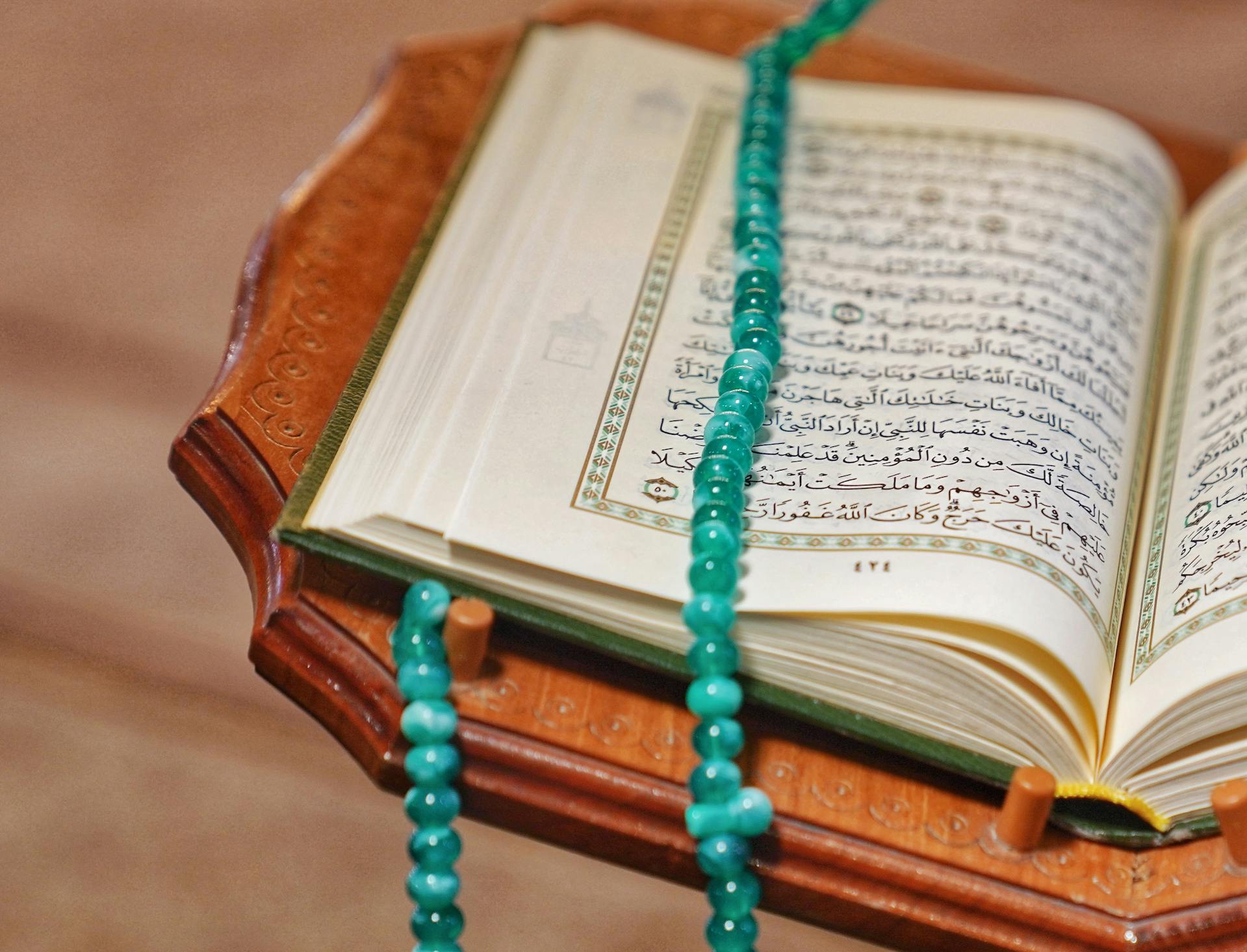 صورة مصحف مفتوح مع مسبحة، تعبر عن التدبر والخشوع في قراءة القرآن الكريم