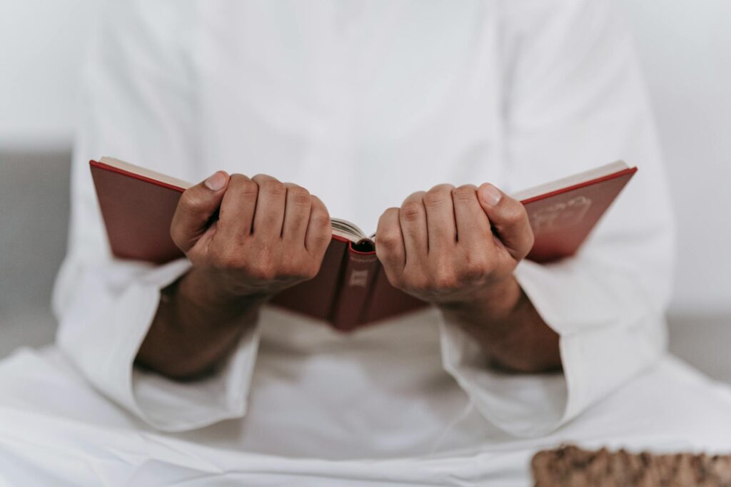 رجل يحمل مصحفًا بين يديه في لحظة خشوع وتأمل، تعبيرًا عن تدبر سورة الفاتحة